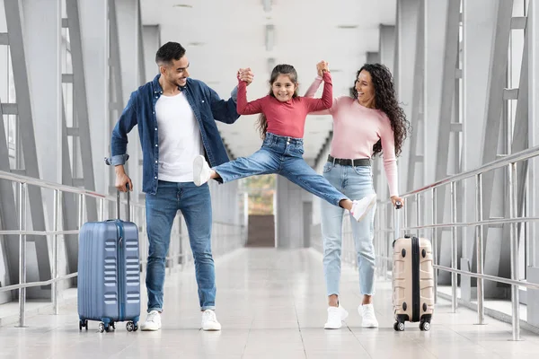 Linda niña divirtiéndose con los padres mientras caminan juntos en el aeropuerto — Foto de Stock