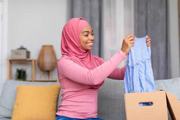 Felice signora musulmana shopaholic ricevere nuovo vestito dal negozio, disimballaggio scatola di cartone, entusiasta di shopping di successo — Foto Stock