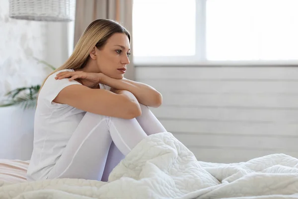 Pensive jonge vrouw zitten op bed alleen, het gevoel down — Stockfoto