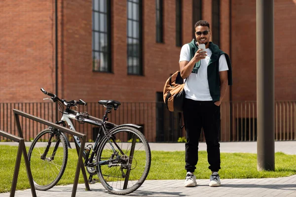 Jovem negro usando telefone andando na cidade — Fotografia de Stock