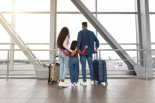 Familj med resväskor tittar ut fönstret på flygplatsen medan väntar på flyg — Stockfoto