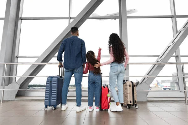 Family With Daughter Looking At Plane Departure Out Of Window In Airport — Stock Photo, Image