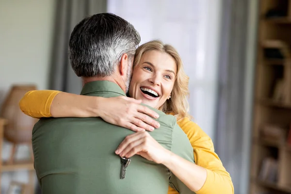 Gelukkig middelbare leeftijd vrouw knuffelen man en het houden van home keys in de hand — Stockfoto