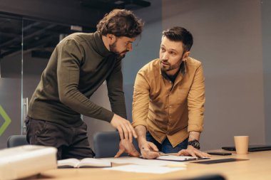Başlangıç projesinde birlikte çalışan erkek arkadaşlar, bilgi yazıyorlar, modern ofiste tartışıyorlar.