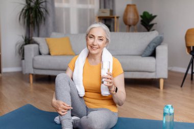 Sağlık konsepti. Aktif son sınıf öğrencisi kadın, yerel spor antrenmanından sonra bardaktan temiz su içiyor.