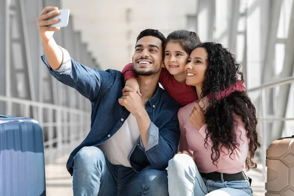 Joyful Middle Eastern Family Of Three Taking Selfie With Smartphone In Airport — Stock fotografie