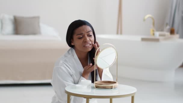 痤疮问题 年轻不幸的非洲裔美国女人坐在浴室里 看着问题的皮肤 检查粉刺或皱纹 — 图库视频影像