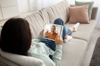 Evdeki rahat koltukta dijital tablet kullanan tanınmayan genç bir kadın babasıyla görüntülü konuşma yapıyor. Bin yıllık bayanın elinde defter, fotokopi alanı, telekomünikasyon konsepti, kolaj