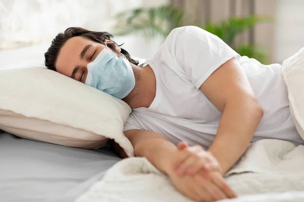 家庭でのウイルス病や発熱に苦しむ医療面マスクの不健康な男 ベッドに横たわって 男性患者はCovid 19から彼の家族を保護します コロナウイルスパンデミックの概念 コピースペース — ストック写真