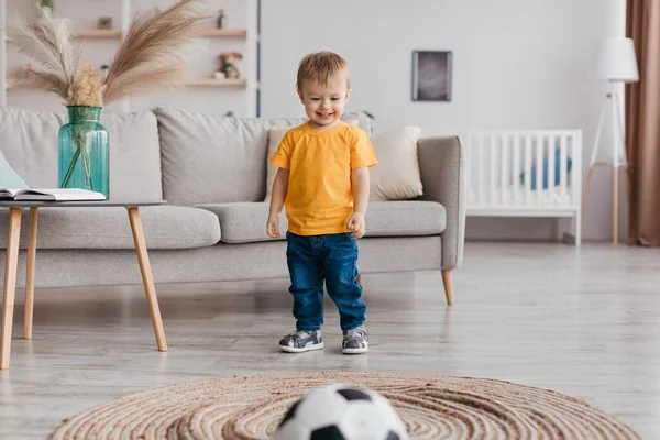 愛らしい幼児の少年サッカーファンの肖像画は リビングルーム 無料のスペースで自宅で楽しんで サッカーボールと笑顔を果たしています 子供のためのスポーツ活動とゲーム — ストック写真