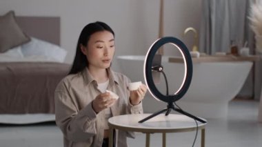 Genç ve güzel Asyalı bir kadın yeni Kore kremi hakkında reklam videosu kaydediyor. Eline sürüyor ve akıllı telefona eleştiri yapıyor, evinde oturuyor, ağır çekimde.