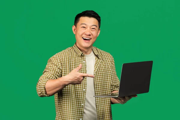 Szczęśliwy Azjata Średnim Wieku Mężczyzna Wskazując Laptopa Uśmiechając Się Kamery — Zdjęcie stockowe