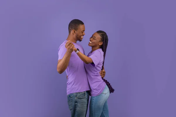 浪漫的概念 在爱情舞蹈和相互凝视中美丽的黑人夫妇的侧面肖像 笑着的年轻大胡子男人抱着他那漂亮的兴奋的女人 长长的辫子 紫色的墙 — 图库照片