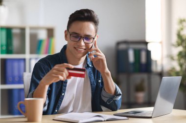 Uzak Ödemeler. Modern ofiste çalışırken cep telefonu ve kredi kartı kullanan Millennial Guy, Çevrimiçi Düzen için ödeme yapan genç erkek girişimci, E-ticaretin tadını çıkarıyor, Boşluğu Kopyala