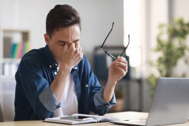 Milenyum Ofisi çalışanlarının gözlerini ovuşturması, masadaki dizüstü bilgisayarla çalıştıktan sonra yorgun hissetmesi, genç girişimcinin gözlüğünü çıkarması, burun köprüsüne masaj yapması, göz süzmesi, yakın çekim yapması,