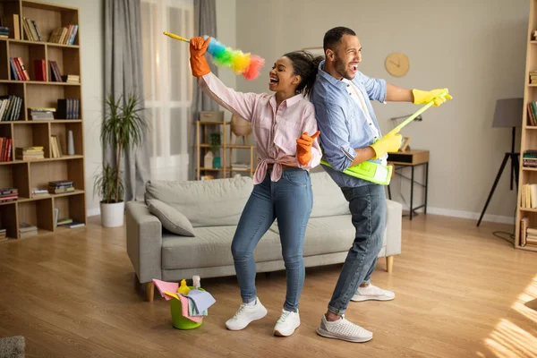 African American Ζευγάρι Καθαρίζοντας Σπίτι Και Διασκεδάζοντας Τραγουδώντας Κρατώντας Σφουγγαρίστρα — Φωτογραφία Αρχείου
