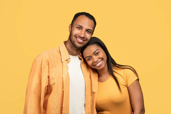 可爱的年轻的非洲裔美国夫妇拥抱在一起 看着相机 微笑在黄色的工作室背景 美丽的黑人女士把头靠在男朋友的肩上 感到快乐 — 图库照片
