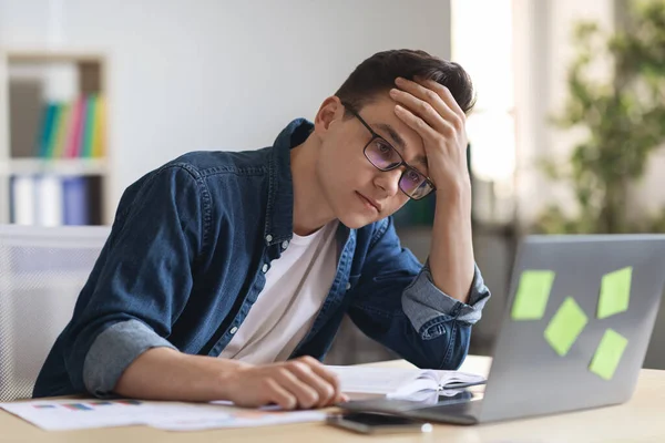 思想的缺乏 疲惫的年轻男性员工看着办公室里的笔记本电脑屏幕 烦躁的千禧年男性坐在电脑前 创造力有问题 精神崩溃 — 图库照片
