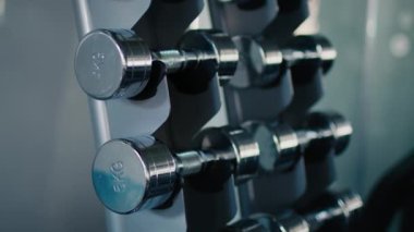 Spor eğitimi konsepti. Spor salonundaki metal dambıllarla yakın çekim. Vücut geliştirme, halter ve spor yaşam tarzı konsepti