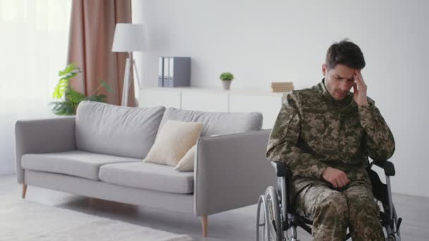 军事创伤 年轻的老兵身穿迷彩服 患有忧郁症和孤独 独自一人坐在轮椅上呆在家里 行动迟缓 空间空虚 — 图库视频影像