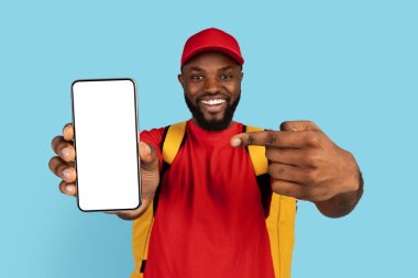 Uygulamada Düzen. Beyaz Ekran ile Boş Akıllı Telefon 'u işaret eden neşeli siyah teslimatçı, termal sırt çantası giyen Afrikalı Amerikan kurye yiyecek teslimatı için mobil uygulama öneren,