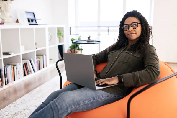 Genç Gülümseyen Siyah Bir Kadının Portresi Kucağında Bilgisayarla Oturma Odasında — Stok fotoğraf