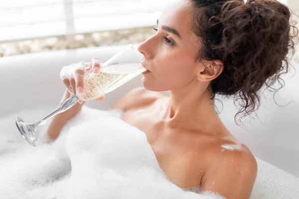 豪華なホテルのバブルバスでリラックスしながら 夢のような千年紀の女性がシャンパンを飲む 自宅でお酒を楽しむ思慮深い若い女性のクローズアップ肖像 — ストック写真