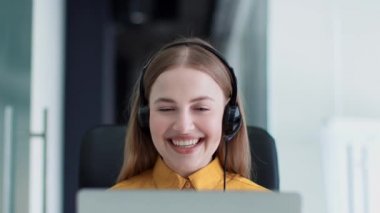 Online danışmanlık. Kulaklık takmış genç mutlu kadın yöneticinin portresi laptopla sohbet ediyor, ortaklığı tartışıyor, yavaş çekim