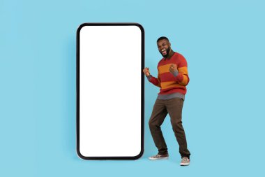 Harika bir teklif. Beyaz Ekranlı Büyük Boş Akıllı Telefon 'un yanında, Siyah Adam' ın Başarısını Kutluyor, Mutlu Afrikalı Genç Amerikalı Erkek Yumrukları ve Heyecanla Bağrışan, Sahte Görüntü