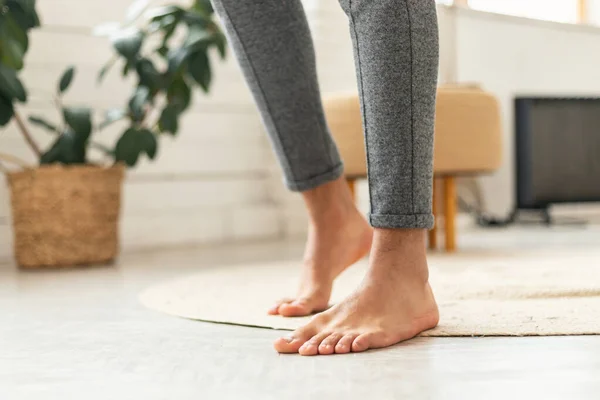 Male Bare Feet Standing On Floor With Radiant Heating System In Modern Bedroom At Home, Wearing Casual Pants. Enjoy Domestic Comfort Concept. Cropped Shot