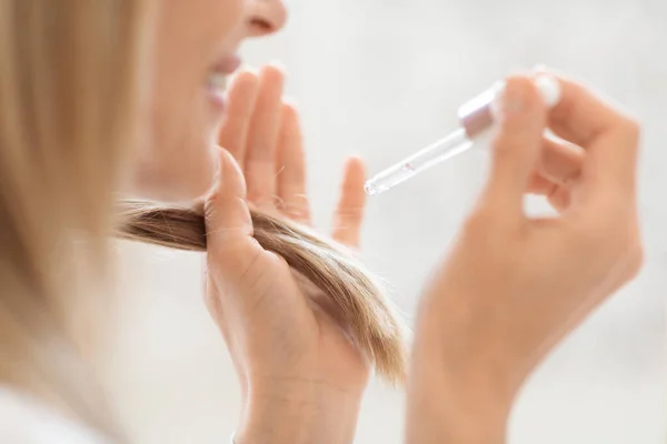 Ritagliato Donna Bionda Che Applica Olio Capelli Alle Estremità Mentre — Foto Stock