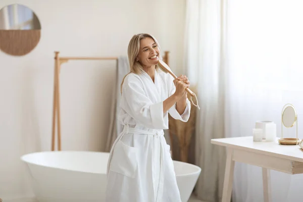 Pozitivní Hezká Blondýnka Županu Zpívá Koupelně Drží Štětec Jako Mikrofon — Stock fotografie