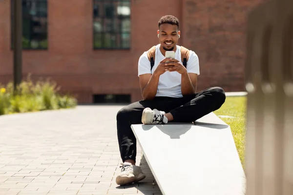 Стильний Афроамериканський Чоловік Дивиться Смішне Відео Смартфон Сидячи Міському Парку — стокове фото
