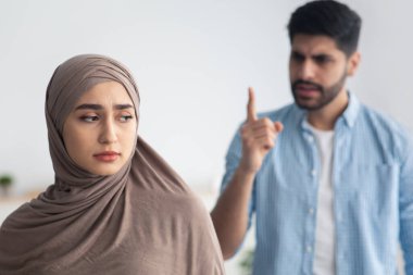 Kızgın koca, evde duran mutsuz Müslüman eşe bağırıyor. Aile içi şiddet ve şiddetten muzdarip, tesettürlü üzgün kadına odaklan. Kötü Evlilik, Mutsuzluk Kavramı