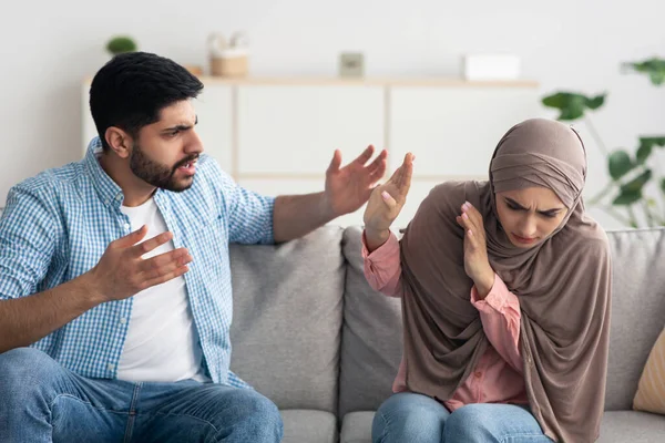 Mad Islamic Husband Shouting At Scared Wife In Hijab At Home. Muslim Lady Suffering From Domestic Abuse And Violence. Marriage Problems And Relationship With Abuser Concept