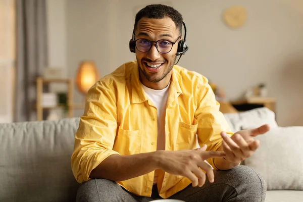 現代の距離通信 人々やガジェットの概念 ビデオ通話やビジネス会議を持っているヘッドフォンで幸せな若い黒人男性 ウェブカメラで笑顔 自宅からオンラインチャット — ストック写真