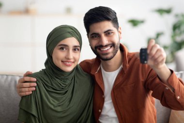 Neşeli Müslüman çift evdeki kameraya gülümseyen yeni araba anahtarını gösteriyorlar. Araba kiralama ve satın alma. Otomobil Sahipliği Konsepti. Seçici Odaklanma