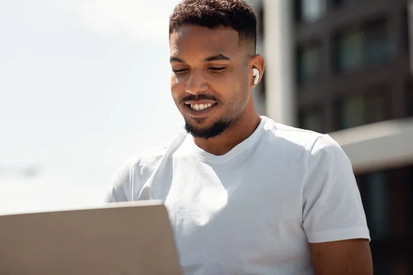 Bonito Homem Negro Com Fones Ouvido Sem Fio Trabalhando Laptop — Fotografia de Stock