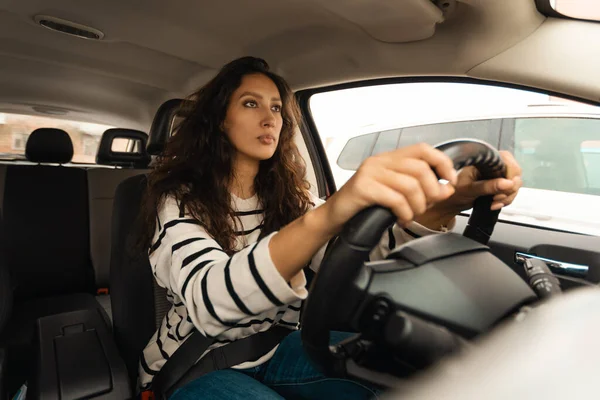 Arabic Female Driver Driving Sitting In New Car Holding Hands On Steering Wheel Looking Aside At Road. Millennial Woman Traveling By Automobile. Transportation, Auto Trip Concept