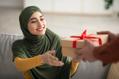 Neşeli Orta Doğulu Eş, Kocasından Hediye Kutusu Aldı, Kollarını Kollarını Açtı, Evde Kollarında Aile Tatili Kutlaması Yapıyor. Hediye Teslimatı. Kırpılmış, Seçici Odaklanma