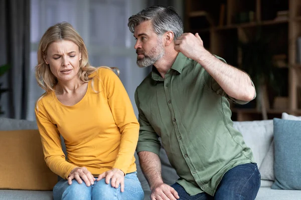 Aile içi şiddet. Saldırgan, Orta yaşlı bir adam, karısını evinde koltukta otururken yumruğuyla tehdit ediyor. Kocasından kaçan korkmuş bir kadın, dövülmüş, acı çekmiş, yakın plan çekilmiş.