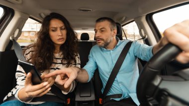 Araba Seyrüsefer Sorunu. Kafası karışmış çift, sürücü koltuğunda oturan, erkek sürücü ve akıllı telefonu işaret eden, kapalı koltukta oturan mobil uygulamayı kullanan. Trafik Uygulaması Konsepti. Panorama