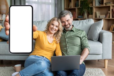 Evde dizüstü bilgisayarla dinlenirken boş akıllı telefonu gösteren mutlu orta yaşlı çift, Yeni Mobil Uygulama veya Web Sitesi, Yaratıcı Kolaj,