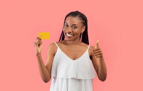 电子货币概念 快乐的年轻黑人女人拿着信用卡 在粉红的工作室背景上摆出大拇指的姿势 美丽的非洲裔美国女性推荐银行服务 — 图库照片