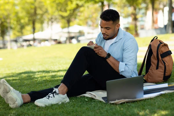 Estudiante Afroamericano Escribiendo Algo Cuaderno Sentado Con Portátil Parque Estudiando — Foto de Stock