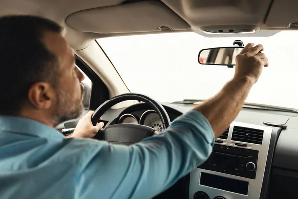 Car Driving. Driver Man Adjusting Rear View Mirror Sitting In New Automobile Riding In City. Back View Of Male Driving Auto. Vehicle And Transportation. Selective Focus