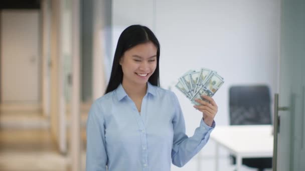 大きな利益だ オフィスのインテリアでボーナスを楽しんで スローモーション カメラに笑みを浮かべて ドル紙幣の多くを示す若いアジアの女性マネージャー — ストック動画