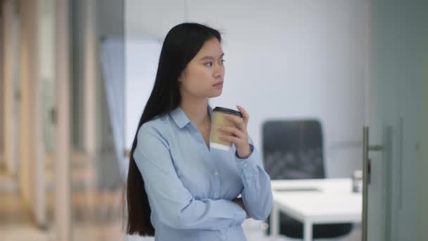 办公室生活方式 年轻宁静的亚洲女人吝啬鬼站在办公室走廊边 端着外卖咖啡 独自度过她的休息时间 把目光投向一边 慢吞吞地移动着 — 图库视频影像