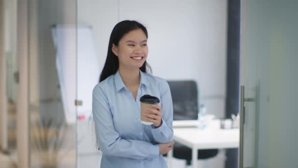 若い幸せな女性従業員テイクアウトエコカップからコーヒーを飲んで オフィスの廊下で笑って 彼女の仕事を楽しんで スローモーション フリースペース — ストック動画