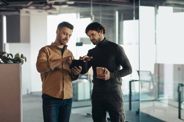 Tablet bilgisayar kullanan, iş kurma projesini tartışan şirket ofisinde kahve içen iki meslektaşın portresi, boş alan. Takım çalışması, işbirliği ve birlikte çalışma kavramı